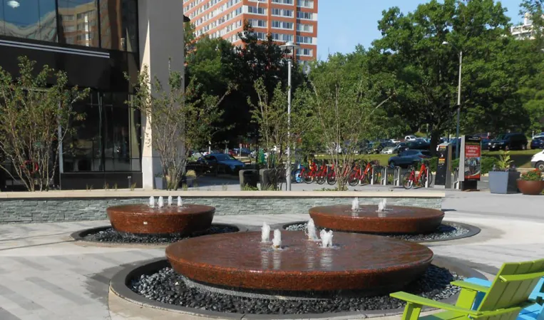Three circular granite fountains with vertical water jets in an outdoor plaza