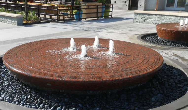 Two circular granite fountains with vertical water jets in an outdoor plaza
