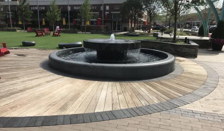 Circular granite fountain with a central water jet cascading over the edge into a lower basin