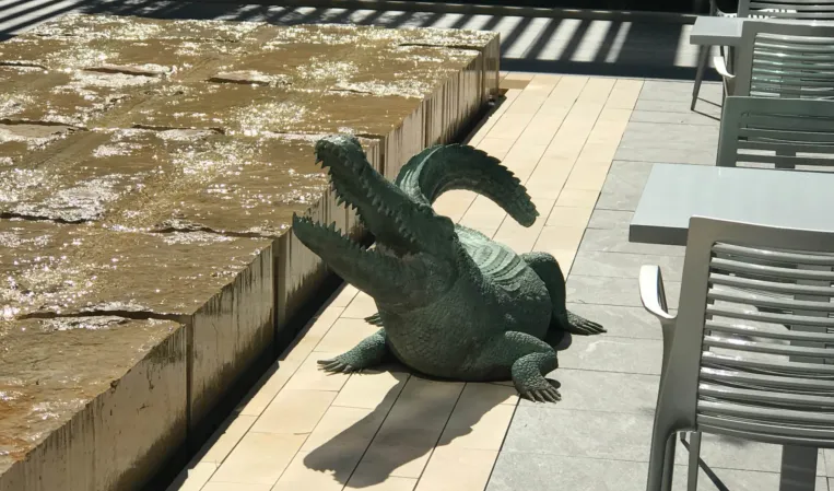 Monolithic limestone water table fountain with a crocodile bronze sculpture next to it