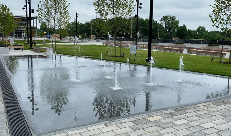 Shallow splash pad with water jets in a landscaped public park