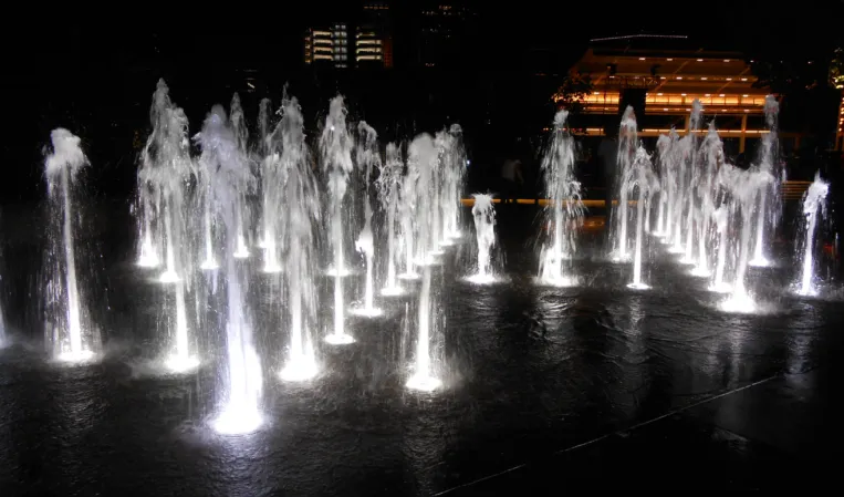 Illuminated water jets in a large urban fountain at night