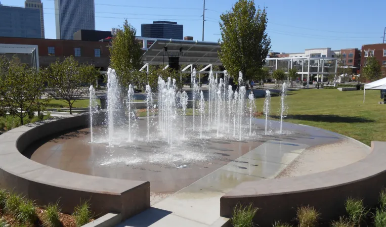 Circular splash fountain with multiple water jets in a landscaped urban park