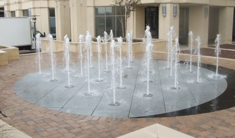 Circular interactive fountain with multiple water jets embedded in a paved plaza