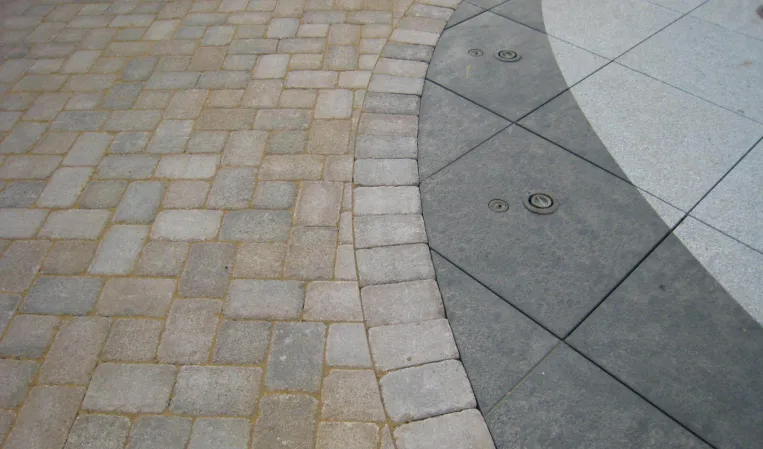 Close-up of curved granite paving with integrated fountain nozzles and surrounding stone pavers