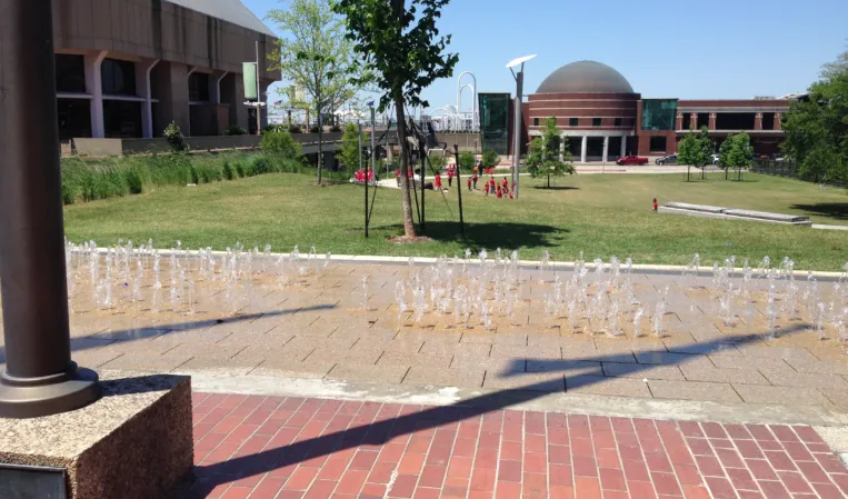 Rectangular interactive fountain with multiple water jets in a landscaped plaza