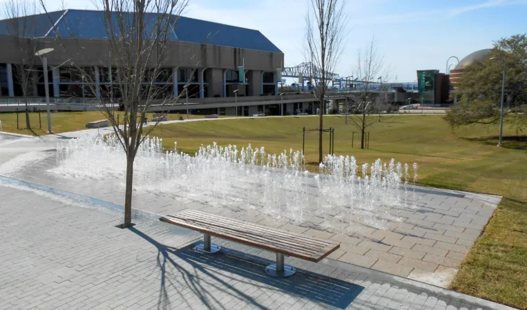 Rectangular interactive fountain with multiple water jets in a landscaped plaza