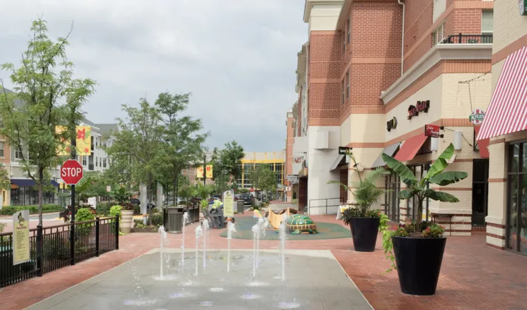 Interactive fountain with water jets along a pedestrian walkway in an outdoor shopping plaza