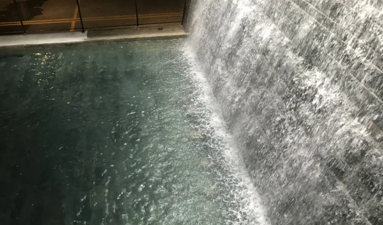 Large indoor waterfall cascading into a dark reflecting pool