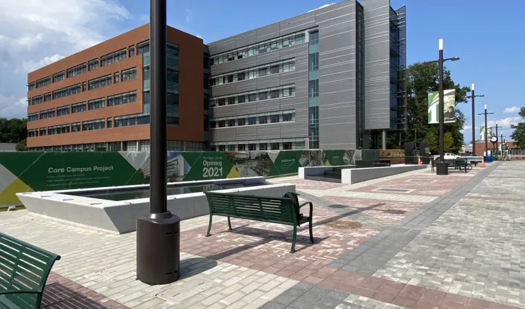 Modern university campus with a granite reflecting pool, benches and paved walkways