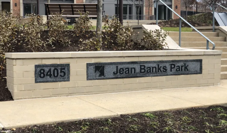 Jean Banks Park entrance sign on a stone wall with landscaped planting