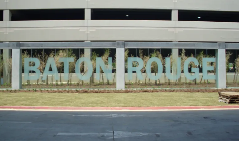 Glass water wall featuring large BATON ROUGE lettering outside a parking garage