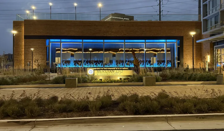 Illuminated water fountain in front of a modern glass-fronted building at dusk