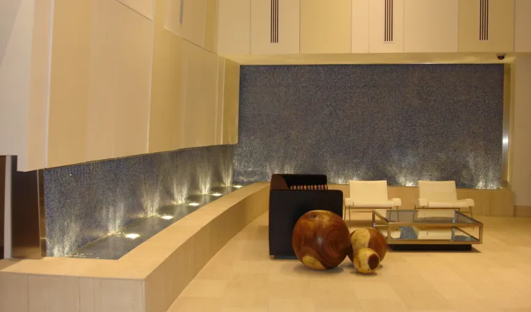 Indoor water feature with illuminated fountains and blue mosaic walls in a modern lounge area