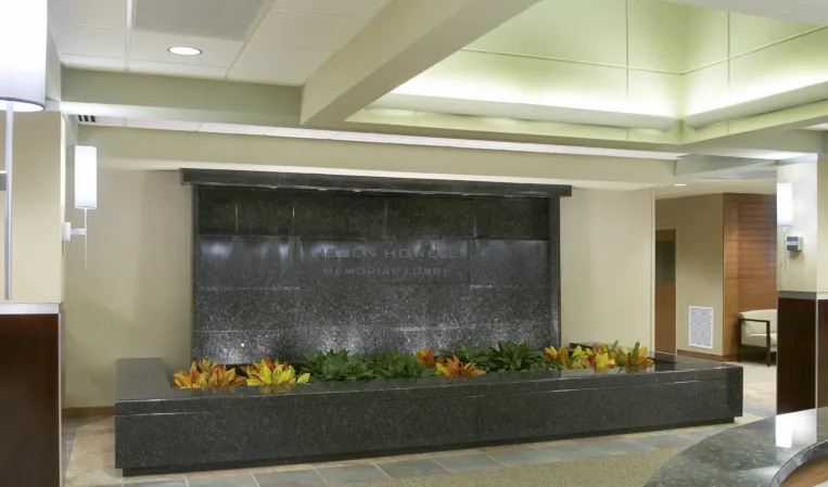 Indoor black granite water wall with a cascading fountain and integrated flower planter