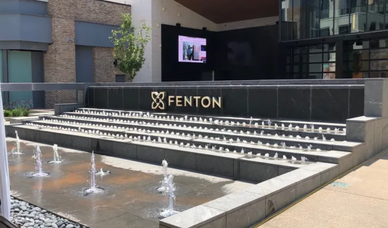 Stepped fountain with water jets and black granite walls outside the Fenton building