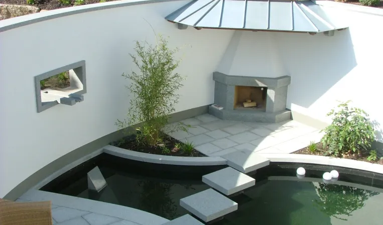 Landscaped courtyard with a curved wall, granite stepping stones and a reflecting pool