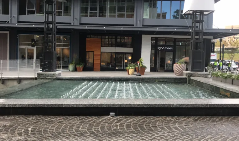 Rectangular fountain with rows of water jets in front of a modern commercial building