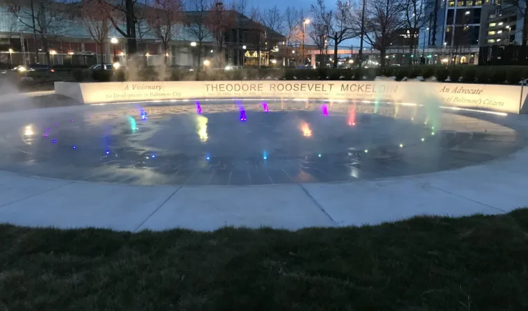 Interactive fog fountain with colorful illuminated jets and mist effects at the Theodore Roosevelt Memorial at dusk