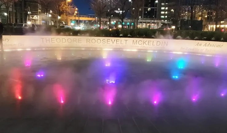 Colorful illuminated fog jets creating a mist display at the Theodore Roosevelt Memorial at night
