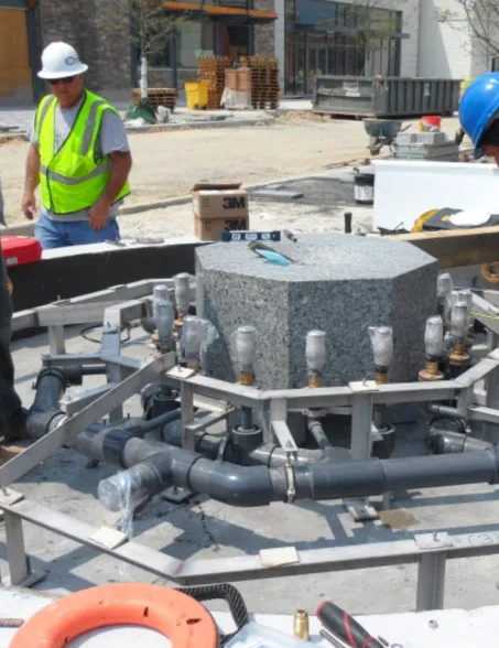 Installation of a circular granite fountain with integrated piping and water technology at a construction site