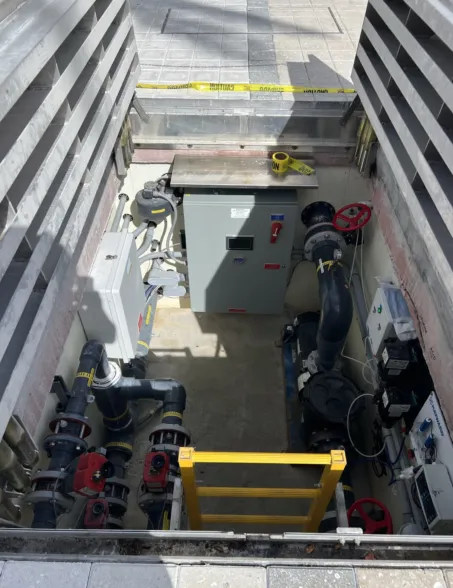 Top view of an underground concrete vault housing water pumps, piping and control equipment