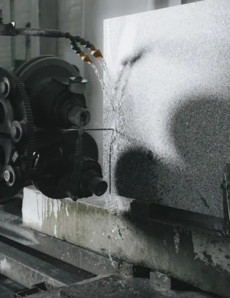 Stone cutting machine processing a granite block with water cooling
