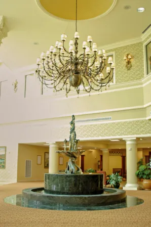 Indoor fountain with a bronze sculpture and circular granite basin beneath an ornate chandelier