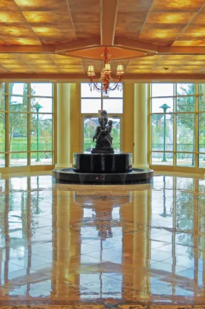 Indoor fountain with a bronze sculpture in an elegant hall with a wooden ceiling and polished marble floors