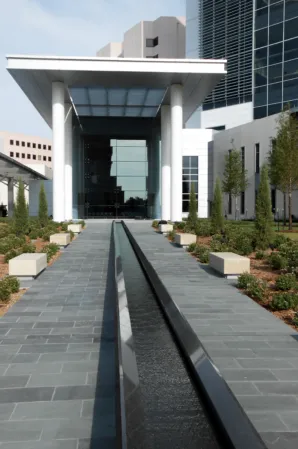 Long, narrow granite water channel leading to the entrance of a modern office building