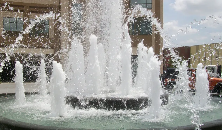 Close-up of powerful water jets spraying into a circular fountain basin