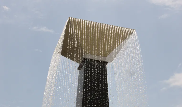 Close-up of a rectangular fountain canopy with cascading water streams against a blue sky
