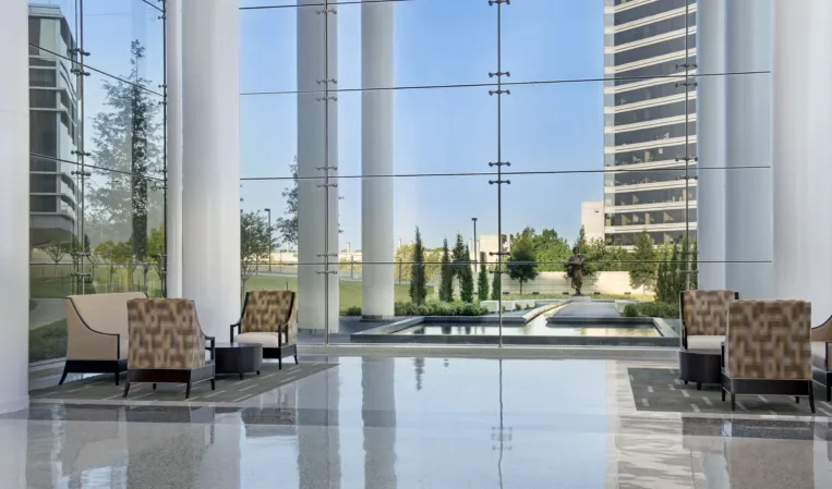 Modern office lobby with floor-to-ceiling windows overlooking a landscaped courtyard with reflecting pools